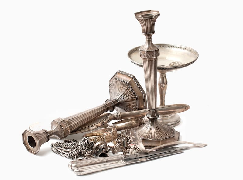 Sterling silver candlestick, cutlery, jewelry on display.